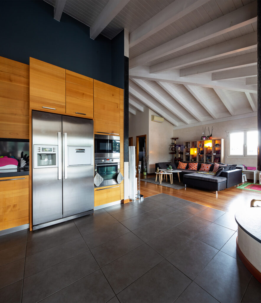 Luxury dark tile flooring in an open kitchen leading to the living room by Hadingers in Fort Myers, Florida